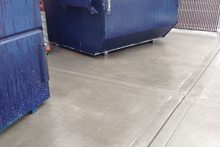 Technician using hot water pressure washer to clean a restaurant dumpster pad in tennessee